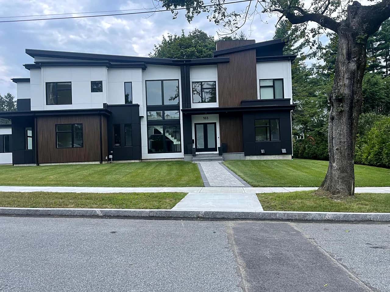 Completed modern home with a white, black and wood panel facade