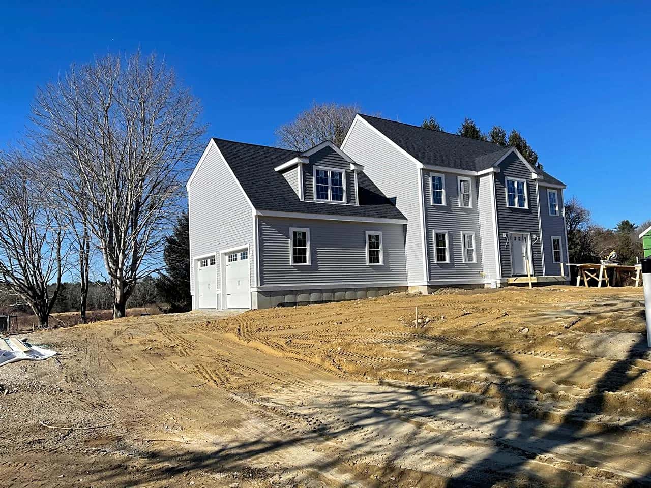 New colonial-style home with gray siding on a freshly graded lot
