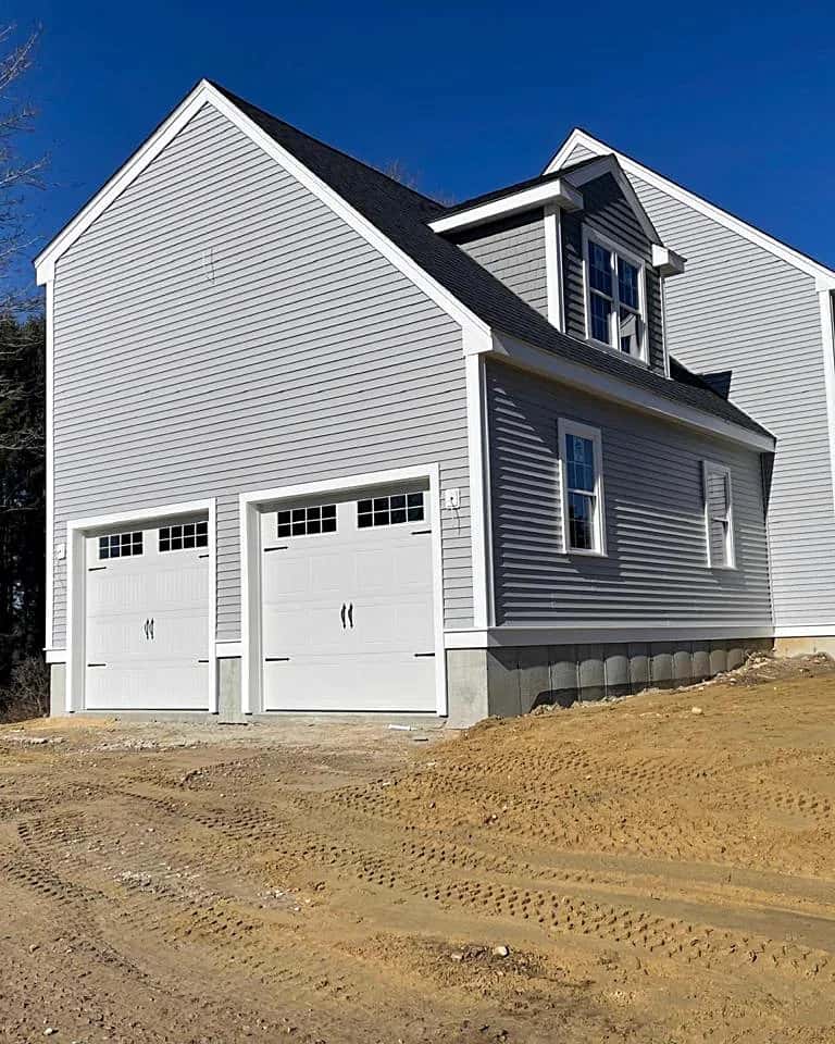 Garage side of a new colonial-style home with two carriage doors