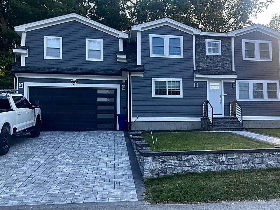 Colonial home in navy siding with a paver driveway