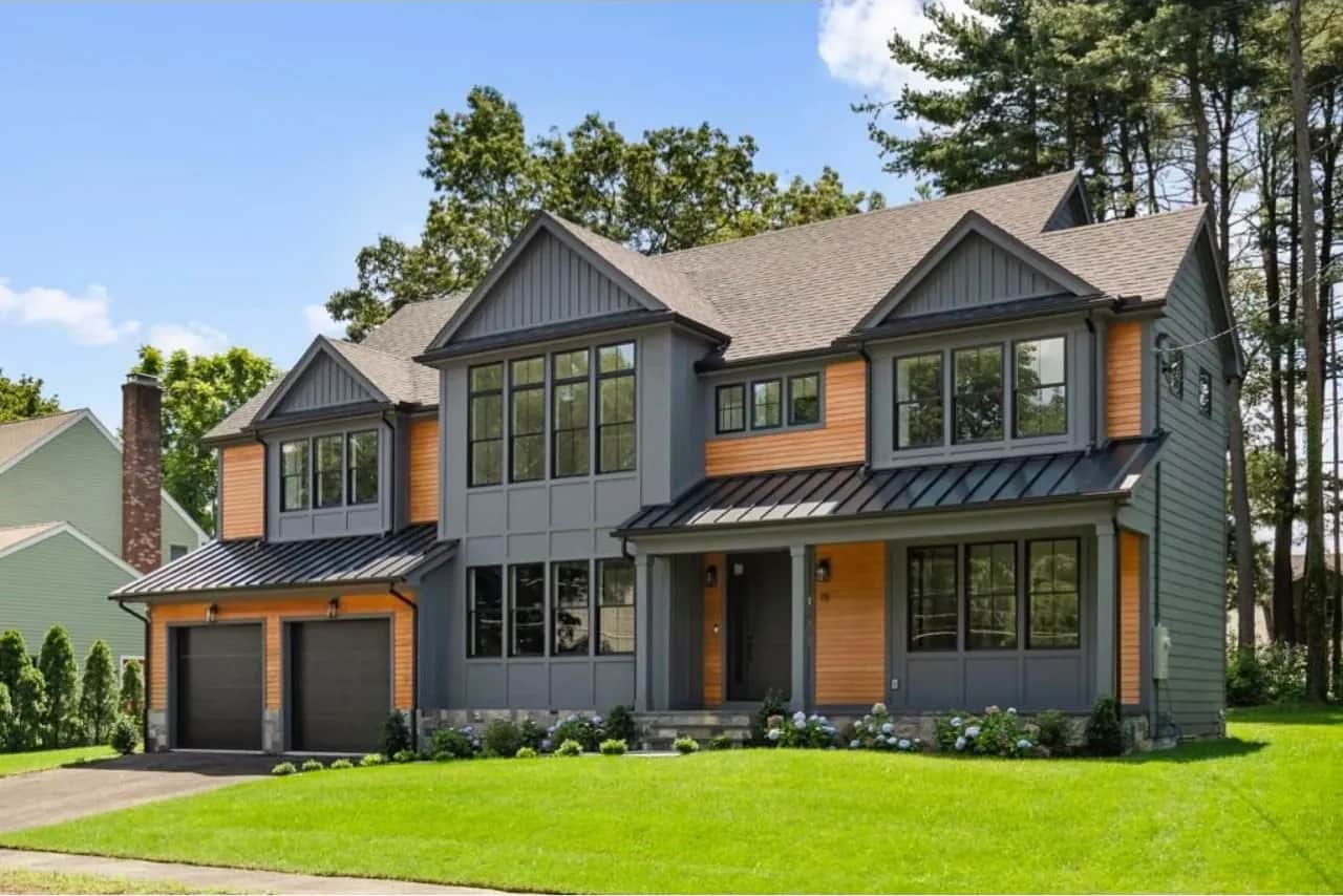 Completed two-story home with gray siding, wood accents and a two-car garage