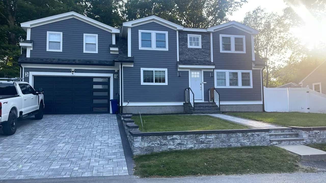 Colonial home in navy siding with a paver driveway